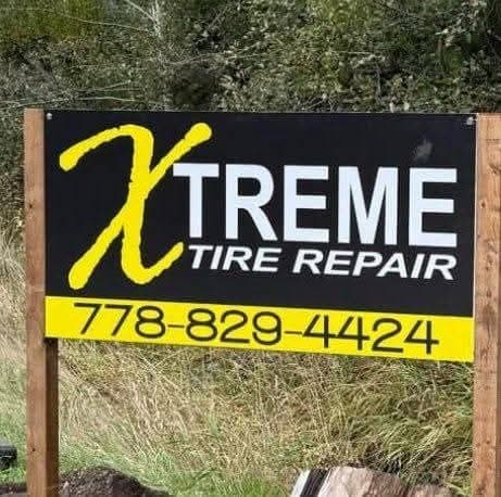 The Xtreme Tire Repair sign at the roadside: yellow X on black, with the phone number 778-829-4424